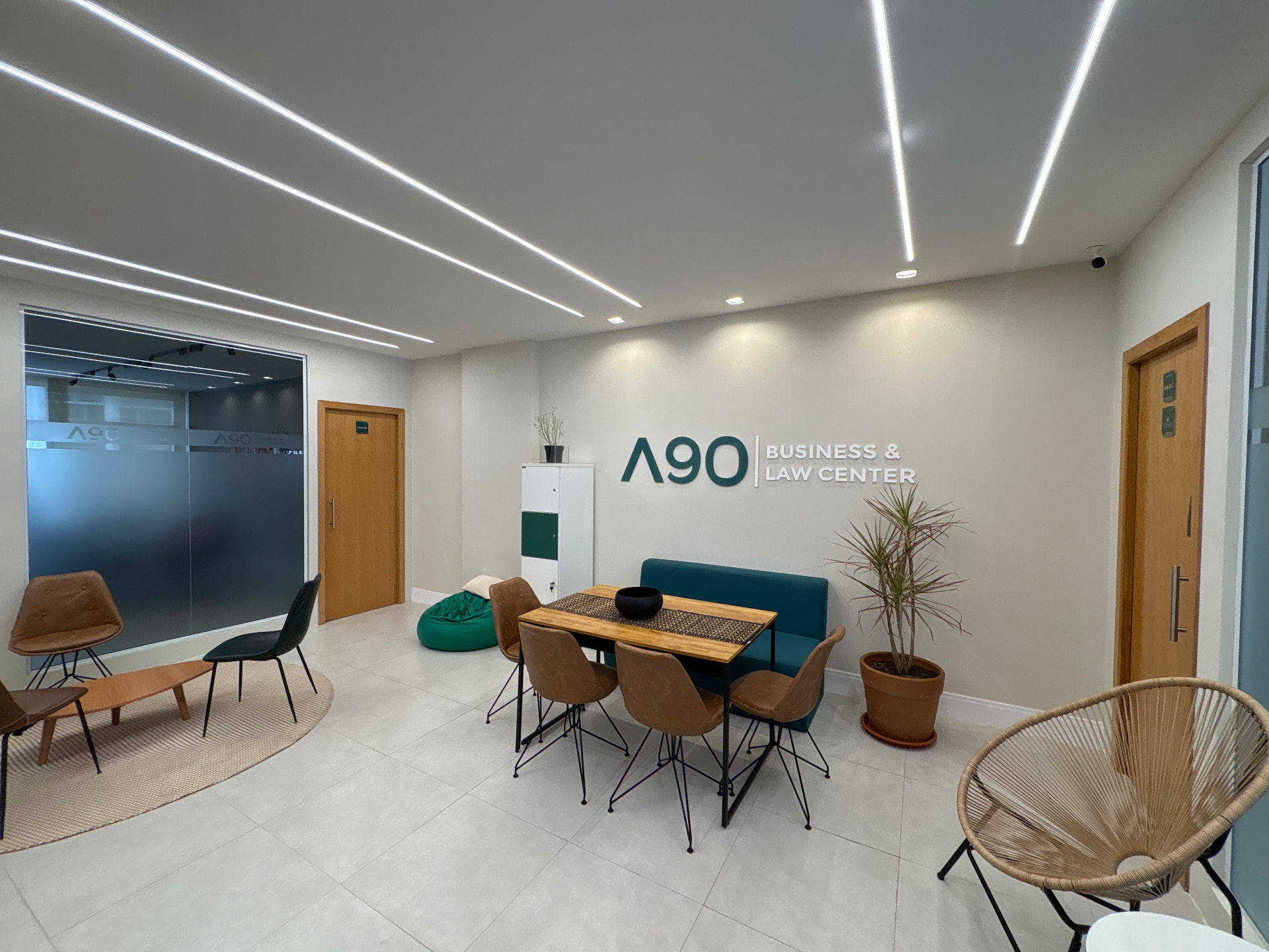 Área de convivência do A90 com mesa, sofá verde e poltronas